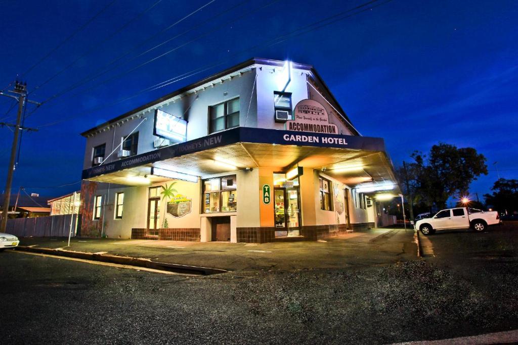 un coche blanco estacionado frente a un edificio en Garden Hotel, en Dubbo