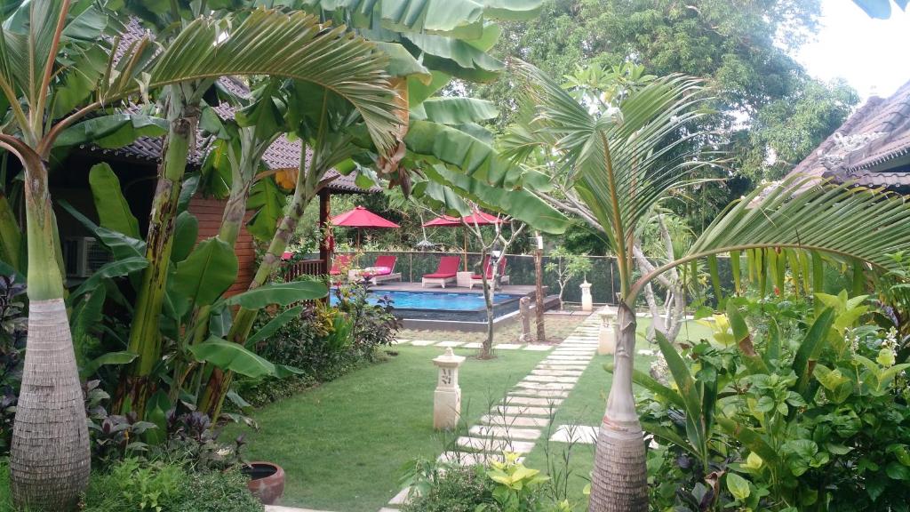 a garden with a pool and some palm trees at Pondok Lembongan in Nusa Lembongan