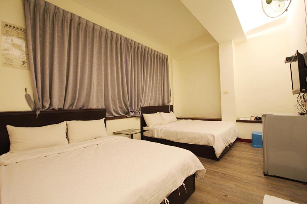 um quarto de hotel com duas camas e uma televisão em Rich House B&B em Kenting