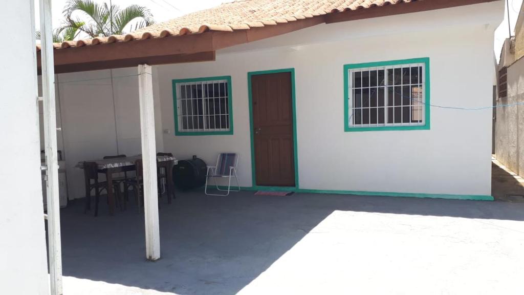 uma pequena casa branca com um alpendre e uma mesa em Casa São Francisco do Sul em São Francisco do Sul