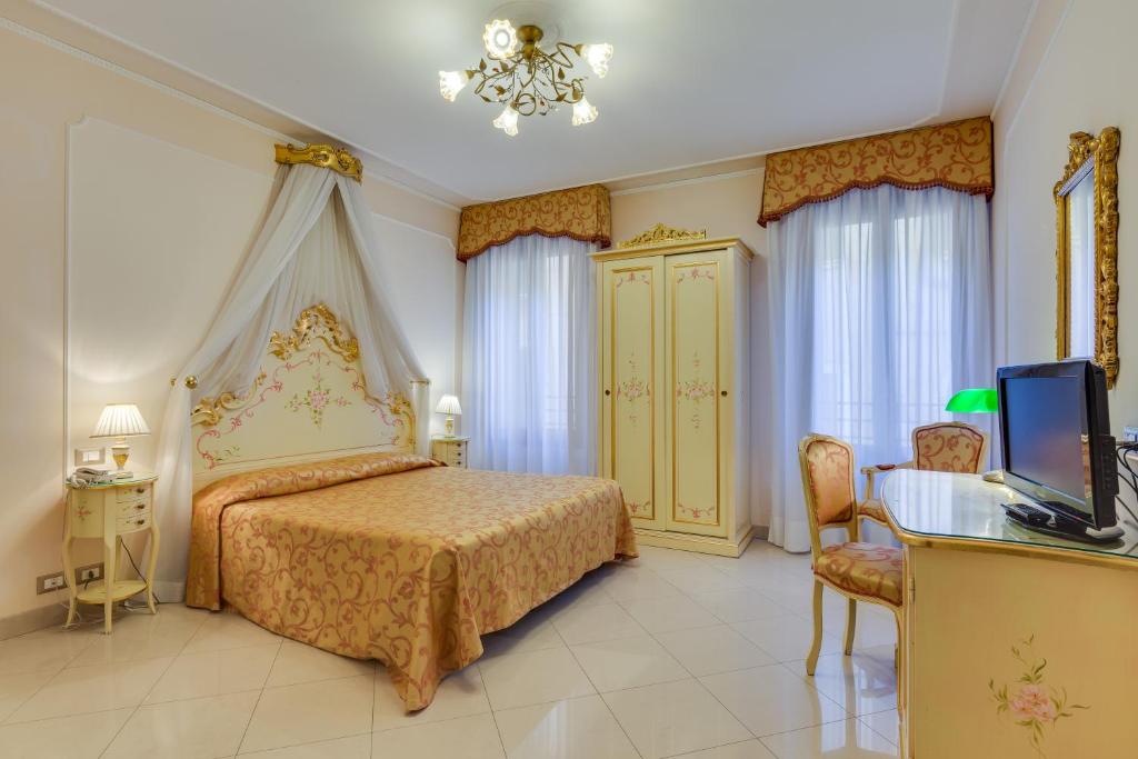una camera con letto, scrivania e TV di Hotel At Leonard a Venezia