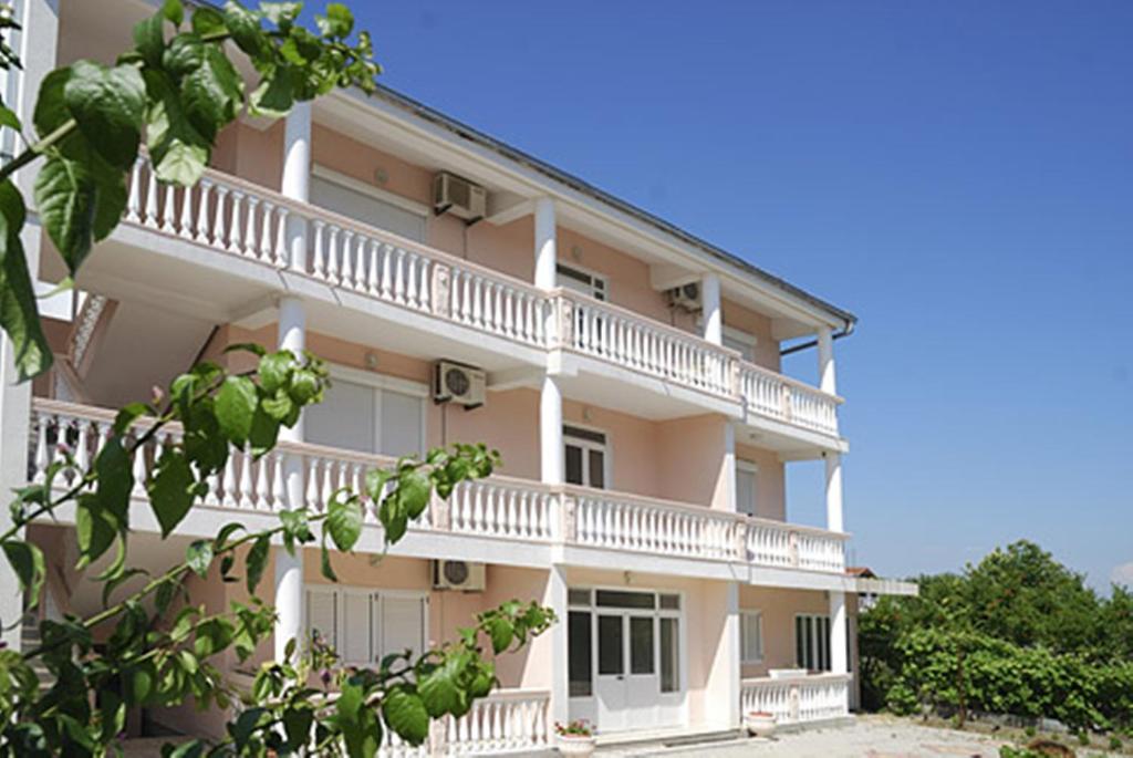 un gran edificio con balcones blancos y árboles en Di Vincenzo Inn, en Ulcinj