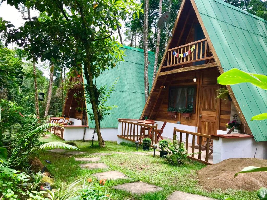 uma cabana na floresta com um telhado verde em Floresta Encantada em Ubatuba