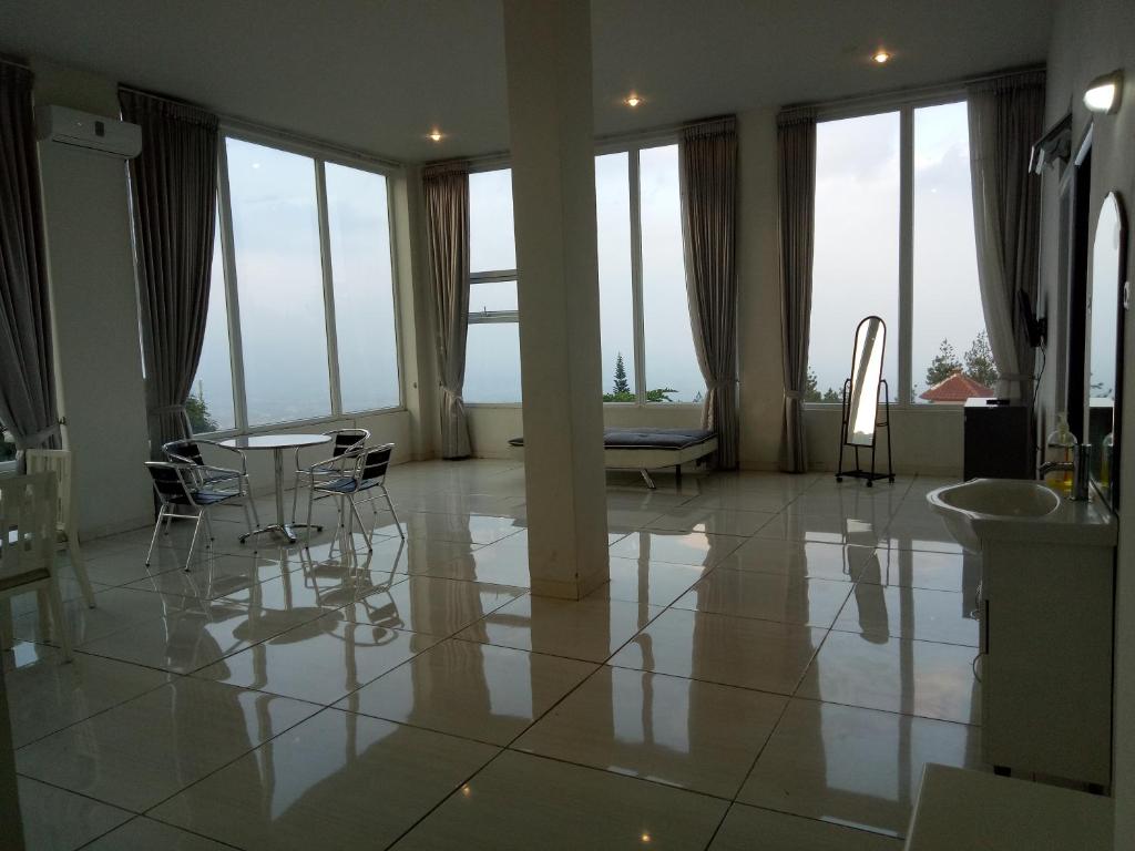a large room with a table and chairs and windows at Villa batu malang panderman hill in Batu