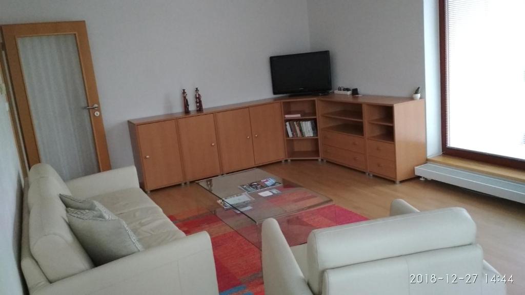 a living room with two white couches and a tv at Apartmán u golfu v Beskydech in Čeladná