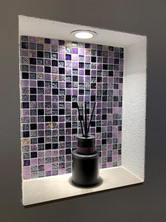 a vase on a shelf with a mosaic tile wall at Eh!Toi Self Motel in Etoy