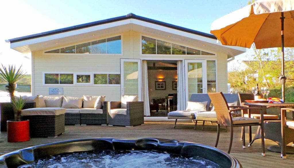 a hot tub on a patio with a house at Chalet M6, The Warren, Abersoch in Abersoch