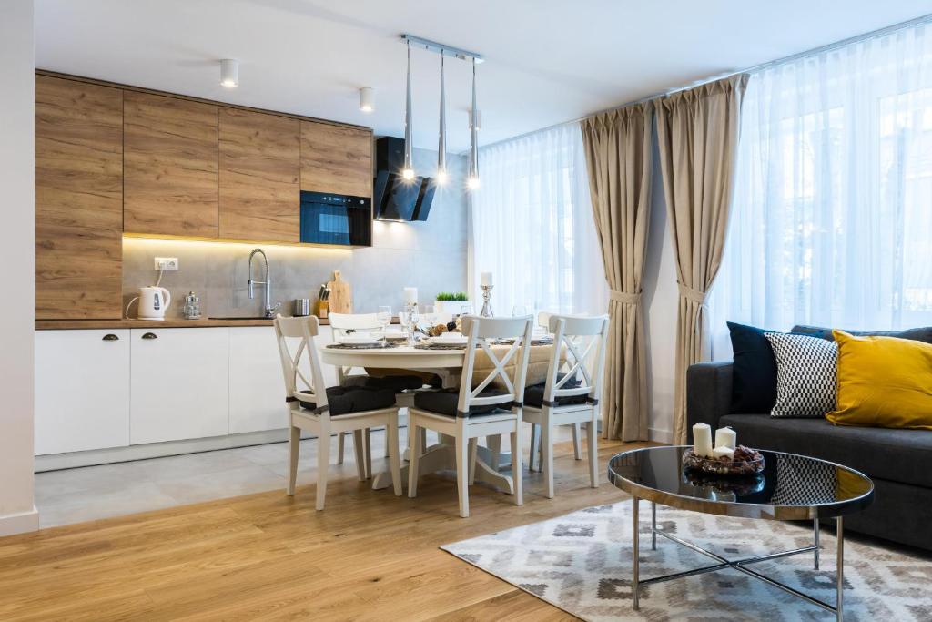a living room with a dining room table and a kitchen at Apartament Przy Krupówkach Odkryj Zakopane in Zakopane