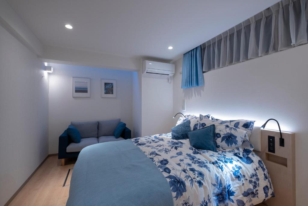 a bedroom with a bed with a blue and white bedspread at Studio Inn Nishi Shinjuku in Tokyo