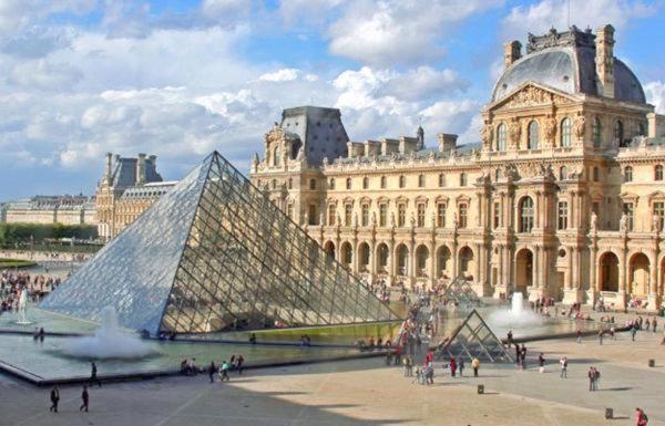 un gran edificio con una pirámide frente a un museo en Opera Louvre Holiday Apartment en París