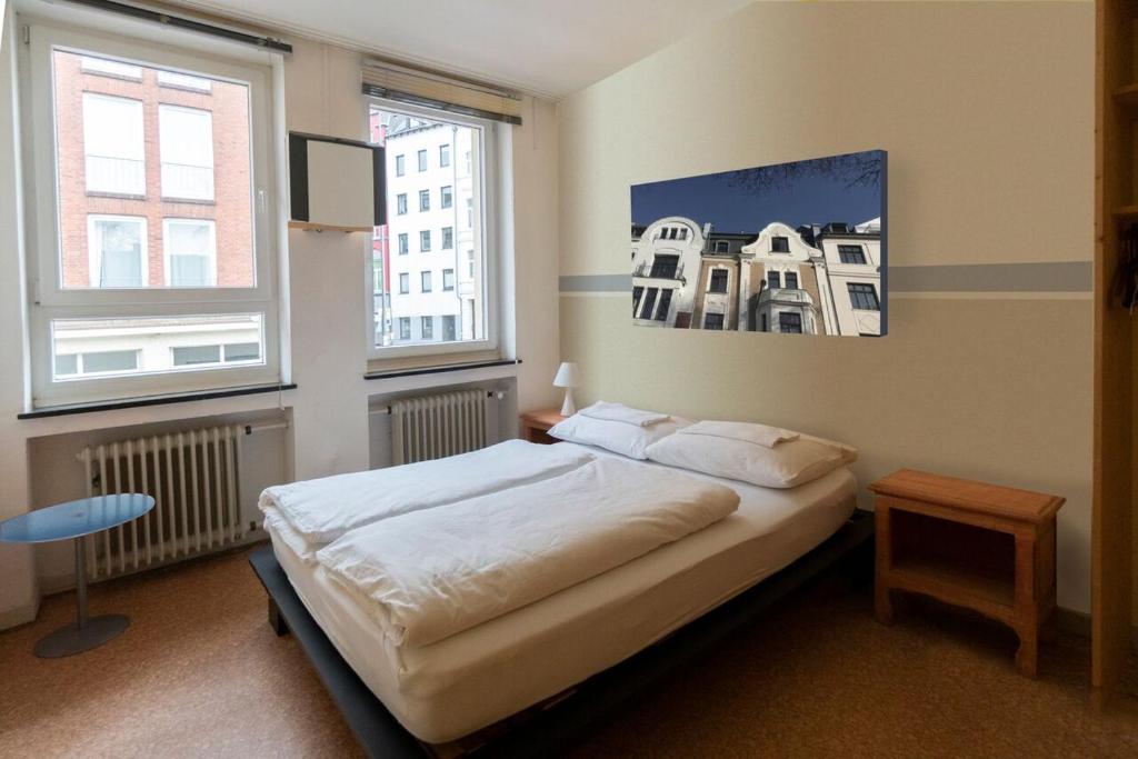 a bedroom with a bed and two windows at Hostel Aachen in Aachen
