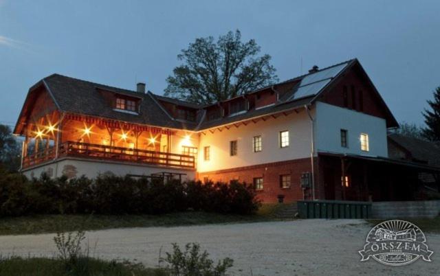 Une grande grange rouge et blanche avec des lumières sur elle dans l'établissement Őrszem Fogadó, à Szalafő