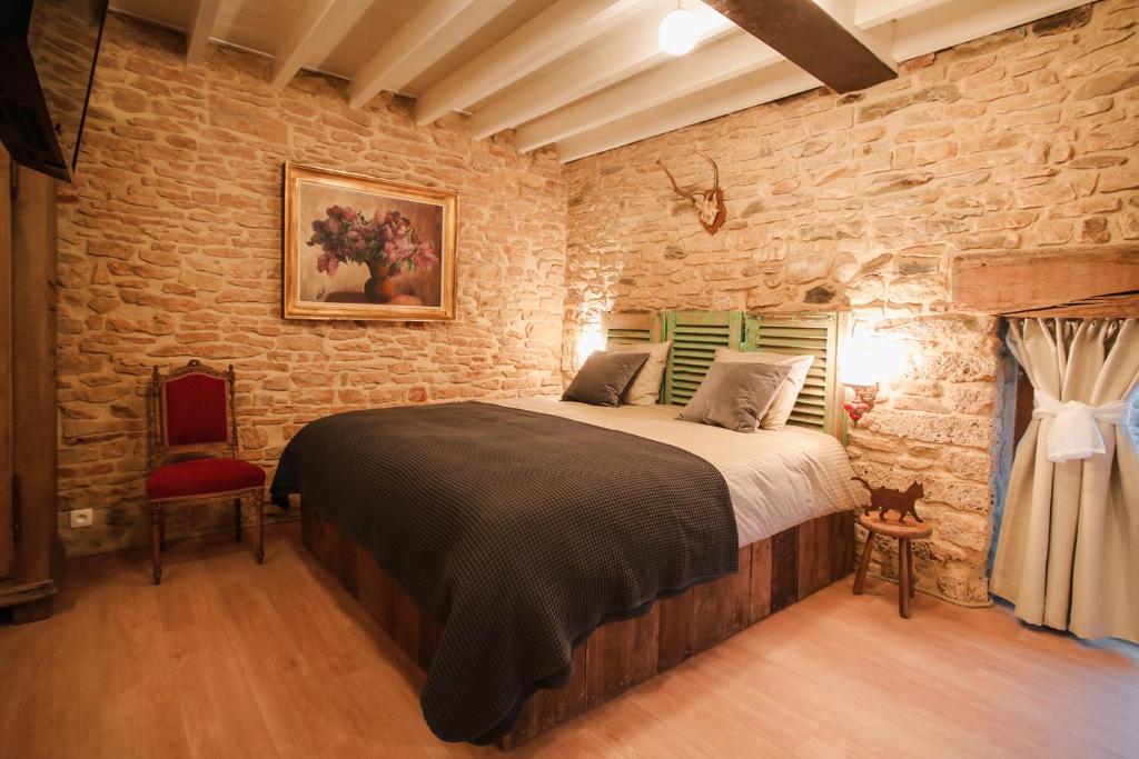 een slaapkamer met een groot bed in een bakstenen muur bij Les Chambres du Chat in Sainte-Cécile