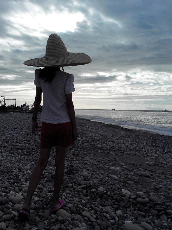 a woman wearing a hat walking on the beach at Amy Walker B&amp;B in Taimali