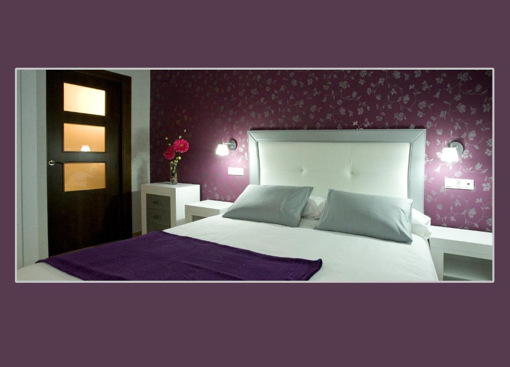 a bedroom with a large white bed with purple walls at Casa Tia Paula in Carrión de los Condes