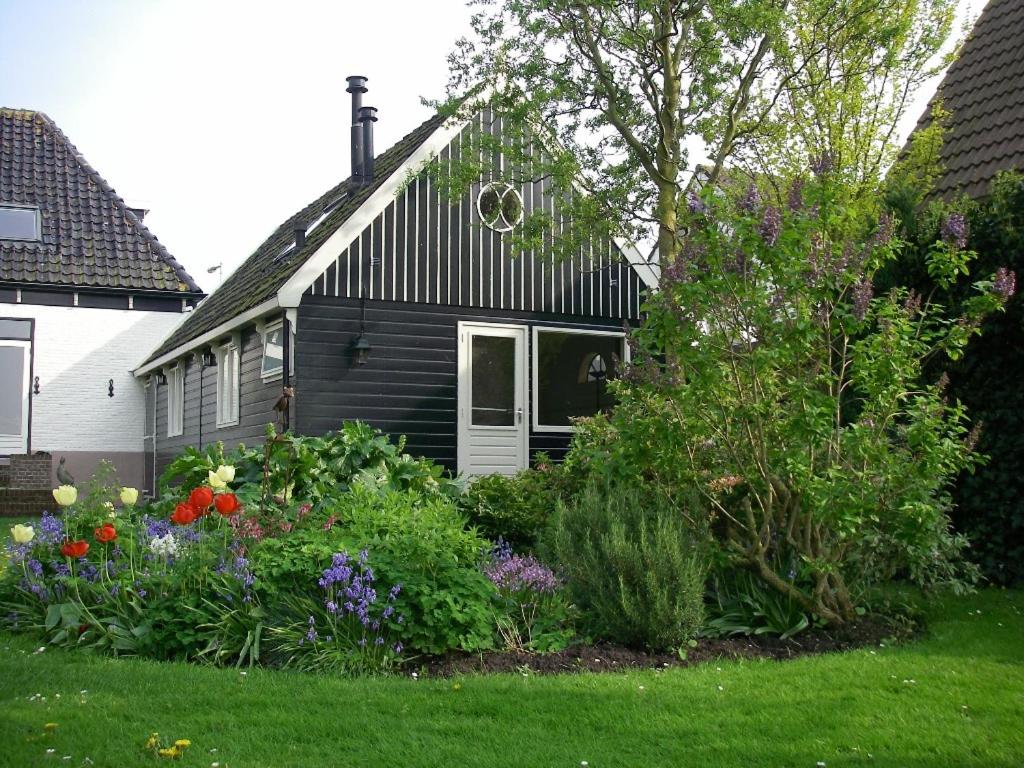 Ein Haus mit einem Blumenstrauß im Hof. in der Unterkunft B&B Waterland in Middelie