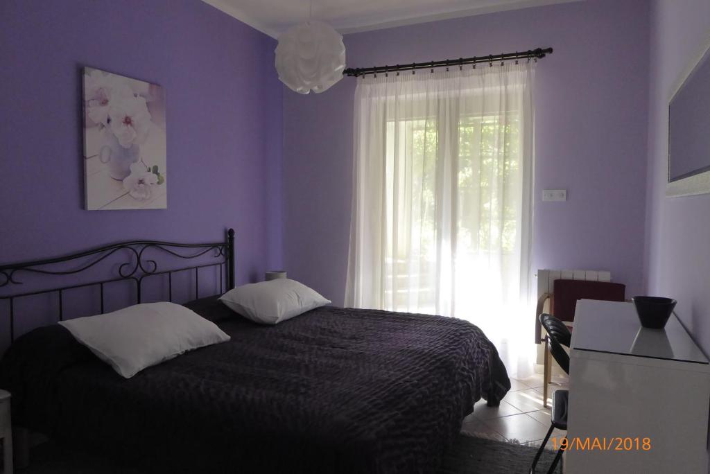 sypialnia z łóżkiem z fioletowymi ścianami i oknem w obiekcie Apartmani DUBAŠNICA w mieście Malinska