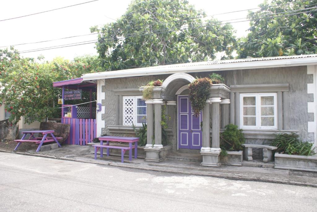 una pequeña casa con puertas moradas y una mesa de picnic en Somewhere Special Guesthouse, en Gros Islet