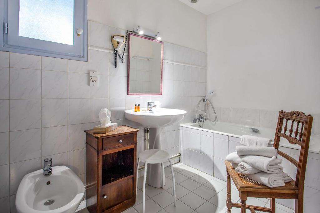 a white bathroom with a sink and a bath tub at La Ferme de Thoudiere in Saint-Étienne-de-Saint-Geoirs