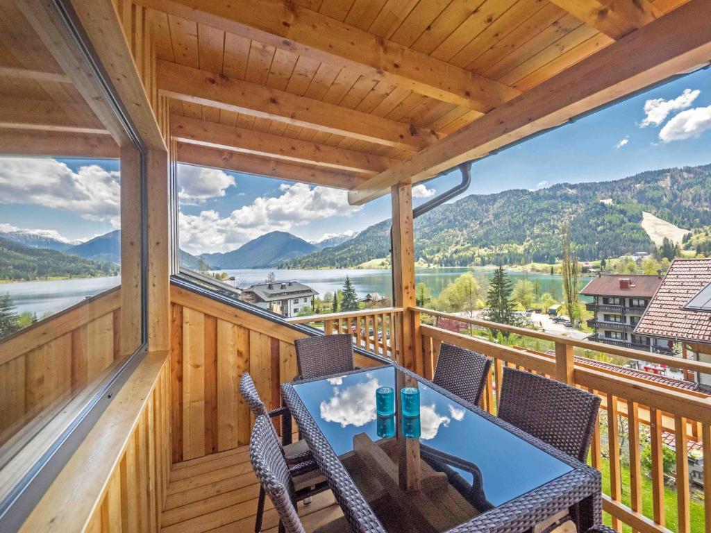 einen Blick vom Balkon einer Hütte mit einem Tisch und Stühlen in der Unterkunft Haus Lackner am Weissensee in Kärnten in Weissensee