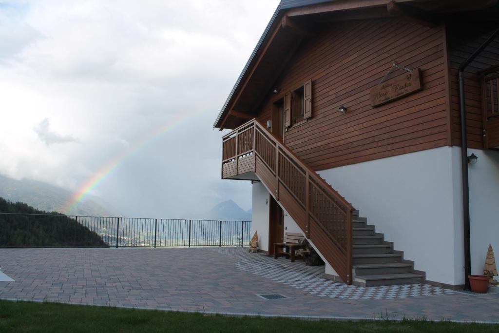einen Regenbogen über einem Haus mit einer Treppe und einer Terrasse in der Unterkunft Agritur Maso Rauter in Vattaro