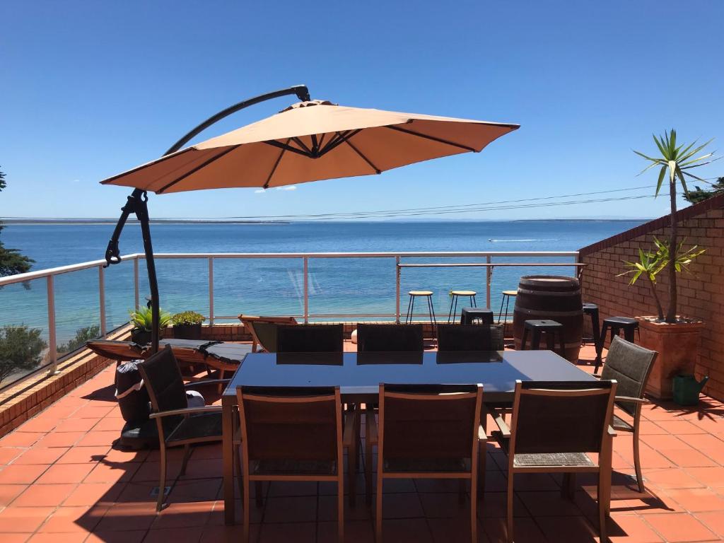 a table and chairs with an umbrella on a balcony at Cowes Beachfront Retreat in Cowes