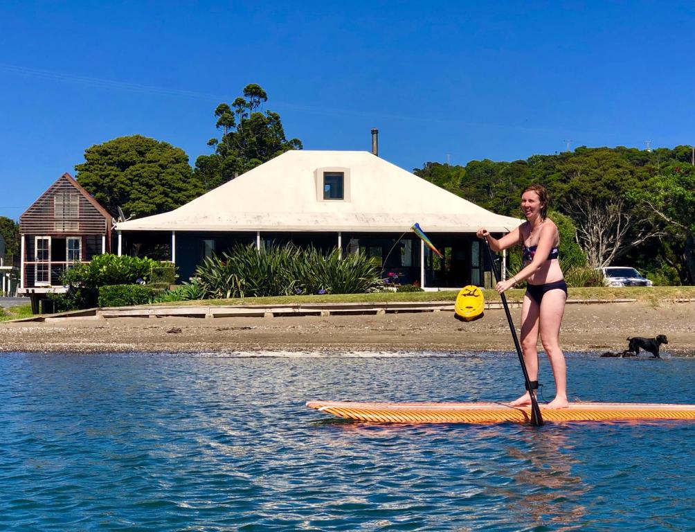 une femme en bikini debout sur une planche de paddle dans l'établissement Absolute Beach front-Tutukaka Harbour, à Tutukaka