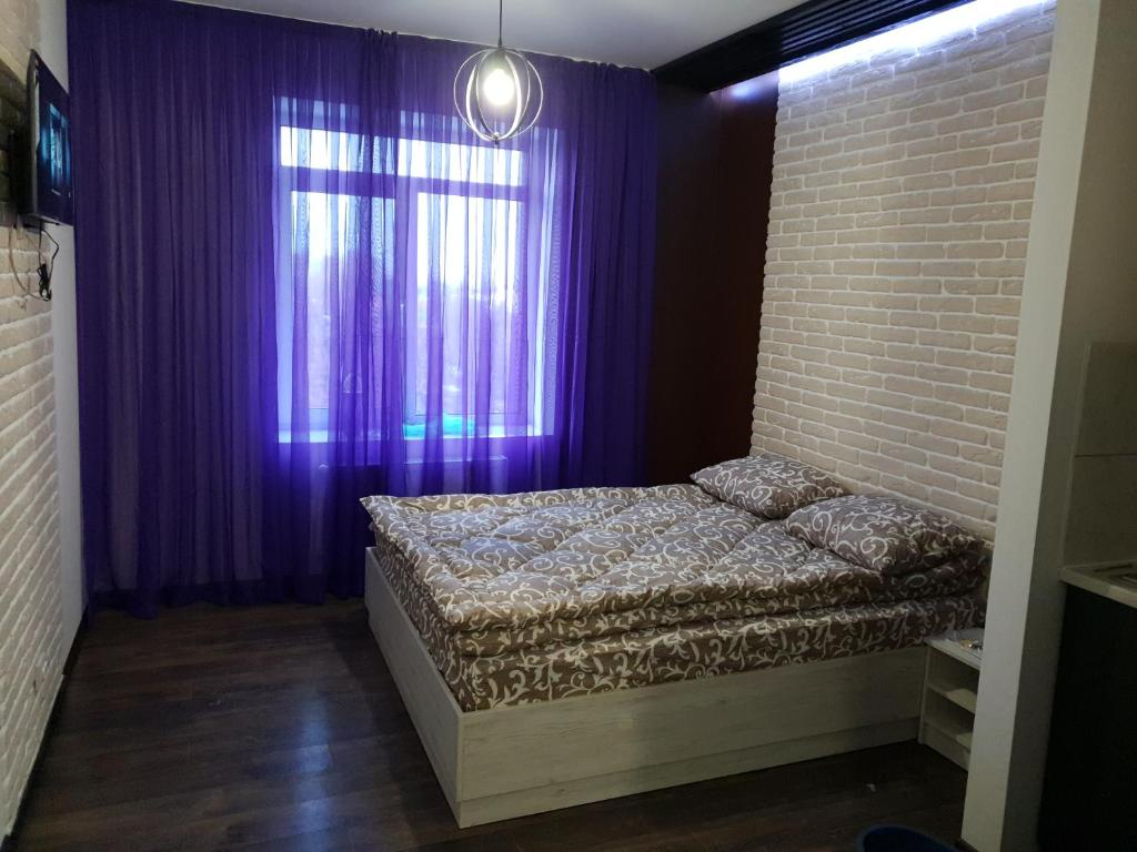 イヴァーノ・フランキーウシクにあるTravel station apartmentの紫色の窓の前にベッドが備わるベッドルーム1室