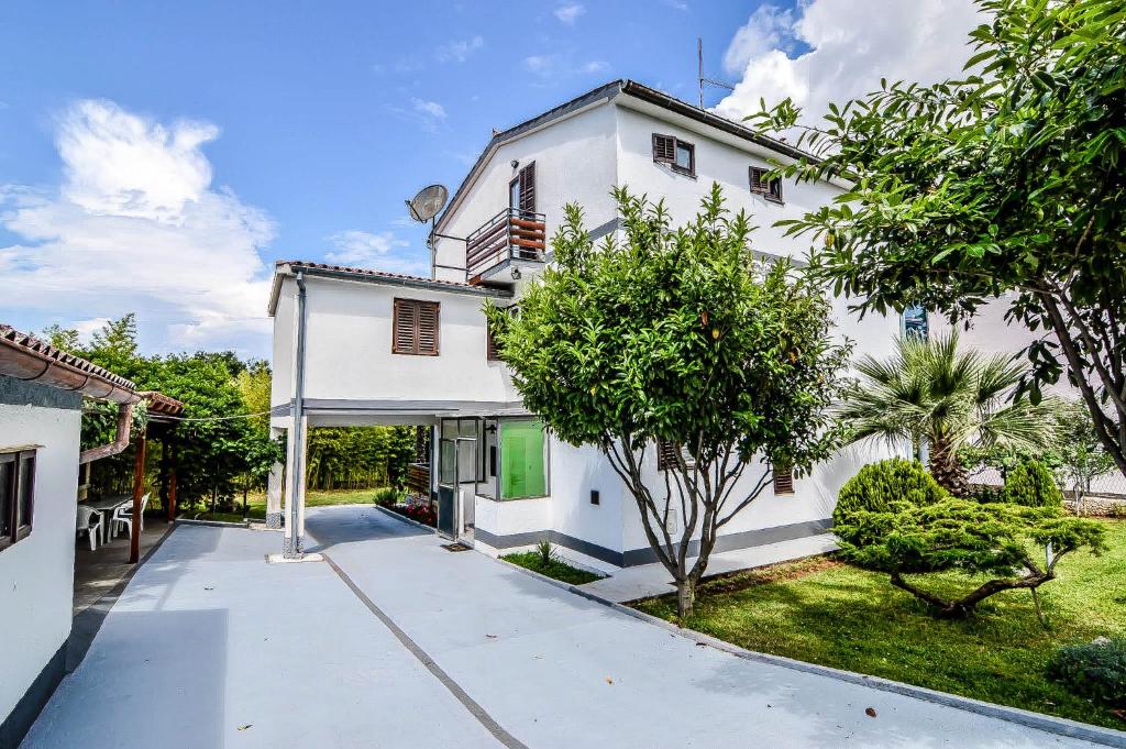een wit huis met een tuin met bomen bij Apartmani Andrea in Pula