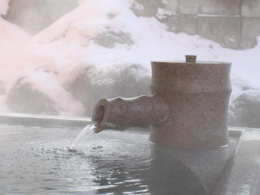 a pipe spewing water into a pool of water at Kusatsu Onsen Hotel Village in Kusatsu