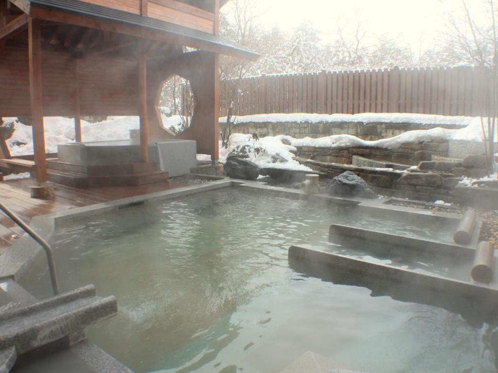 a pool of water in front of a house with snow at Kusatsu Onsen Hotel Village in Kusatsu
