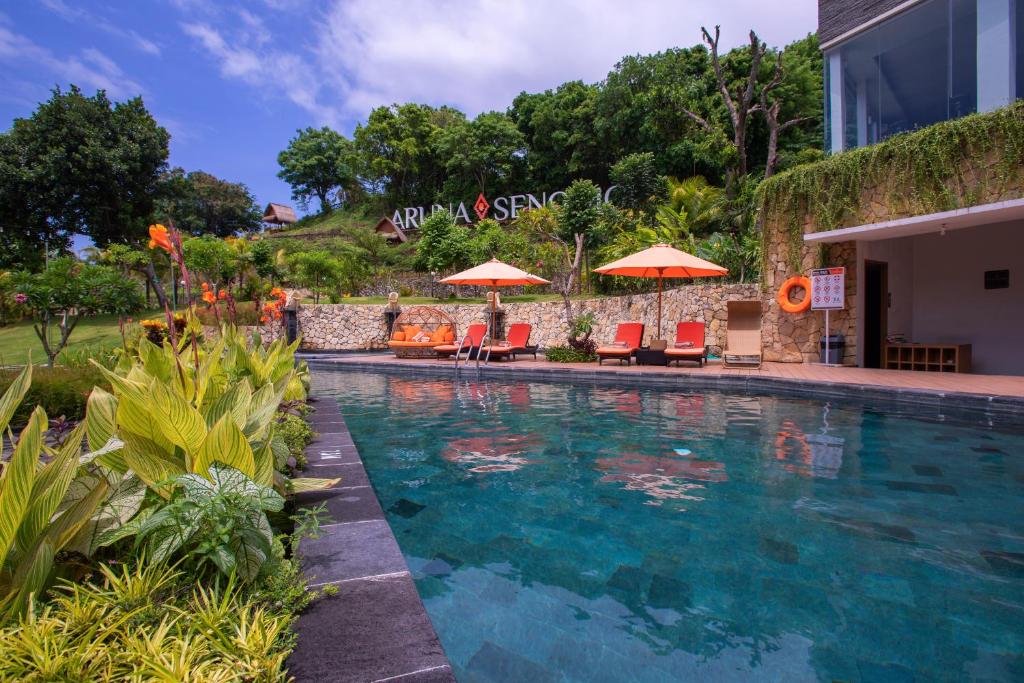 a swimming pool with chairs and umbrellas next to a building at Aruna Senggigi Resort & Convention in Senggigi 