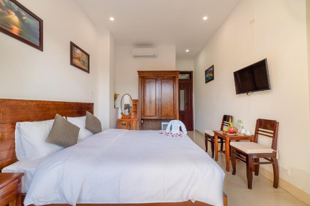 una camera con un grande letto bianco e una TV di Hanh Nhung Villa a Hoi An