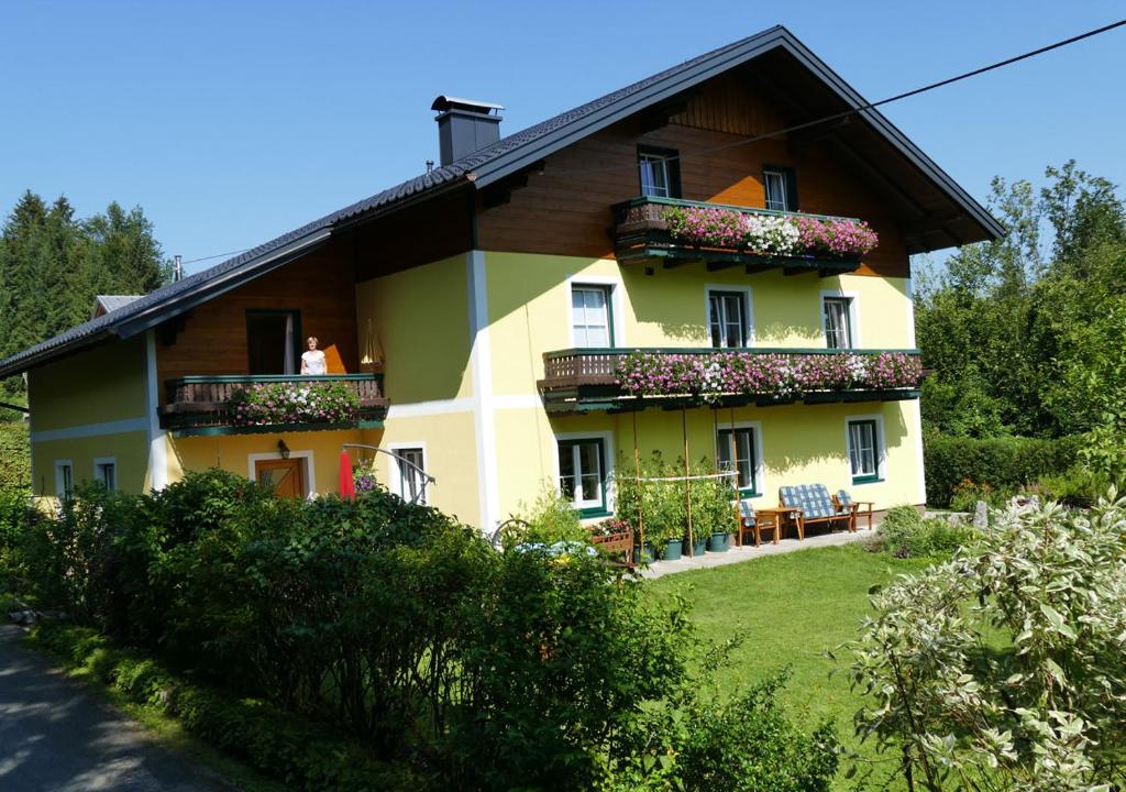 żółty dom z kwiatami na balkonach w obiekcie Haus Schöffau w mieście Strobl