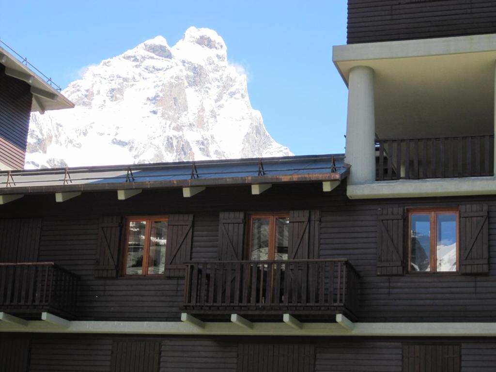 a building with a snow covered mountain in the background at Appartamento Centro Breuil CIR 0139-0142 in Breuil-Cervinia