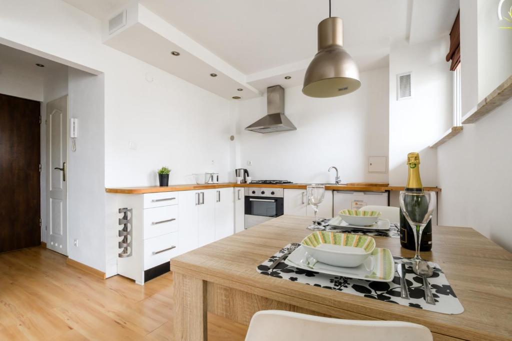 a kitchen with white cabinets and a wooden counter top at Labo Apartment Muranów in Warsaw