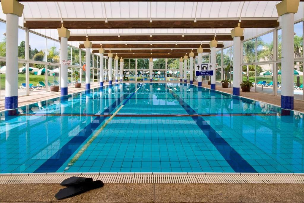 a large swimming pool with blue tiles on the floor at Holiday garden apartment in Caesarea