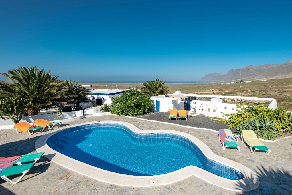 a large swimming pool with chairs and a beach at Finca Las Laderas in Las Laderas