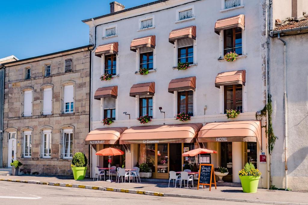 a building with tables and chairs in front of it at Le Commerce in Dompaire