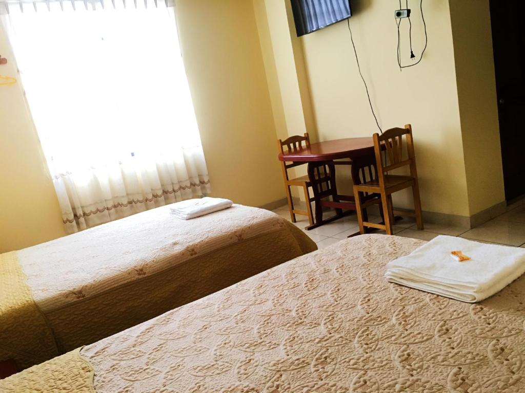 um quarto de hotel com duas camas e uma mesa e uma janela em Sandel em Barranca