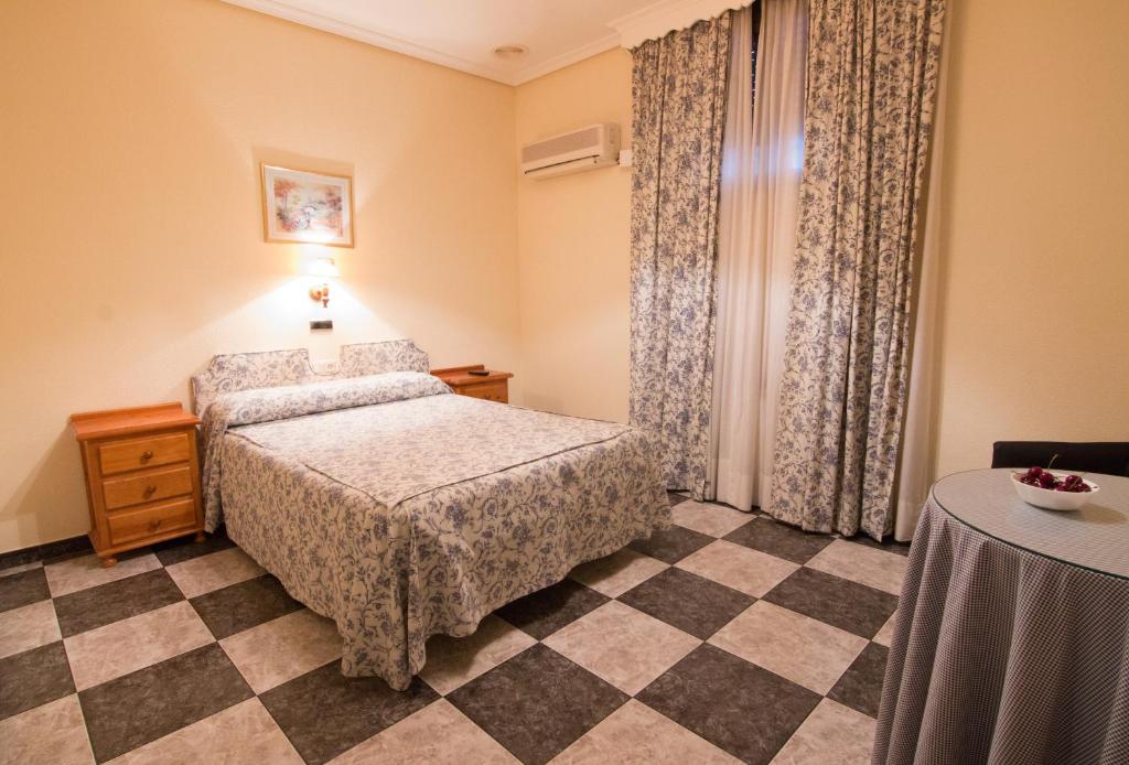 a bedroom with a bed and a checkered floor at Hostal Santa Ana in Madridejos