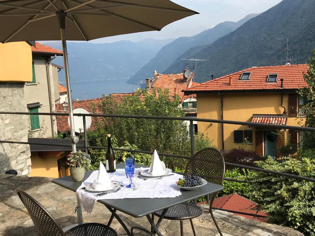 una mesa con sillas y una sombrilla en el balcón en Casa delle Rose, en Faggeto Lario 