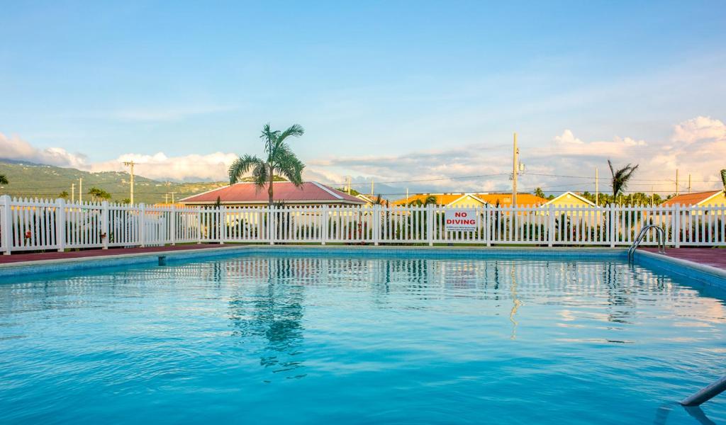 a swimming pool with a white fence and blue water at Casa Victoria Golf Retreat in Caymanas