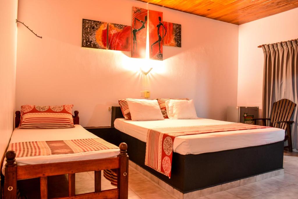 a bedroom with two beds and a table at Hotel Apollo in Hikkaduwa
