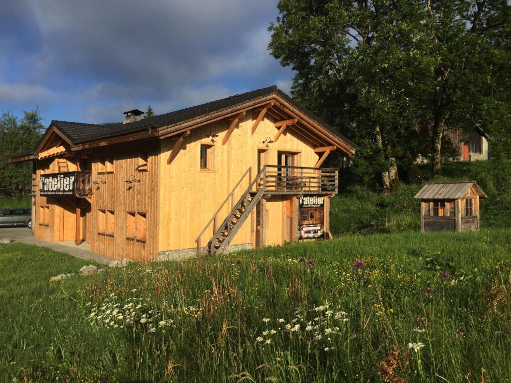 a large wooden cabin in a field of grass at Le Grenier à Luge in Les Gets