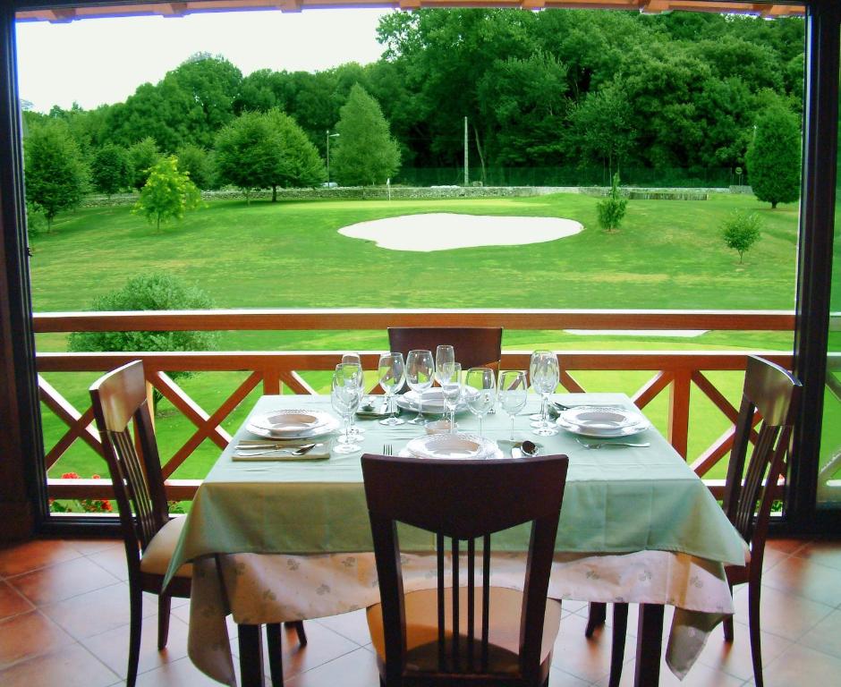 a table with a view of a golf course at Hotel Aldama Golf in Quintana de Llanes