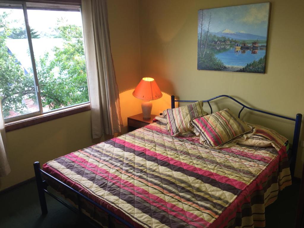 um quarto com uma cama, um candeeiro e uma janela em Cabaña Hagemann em Puerto Varas