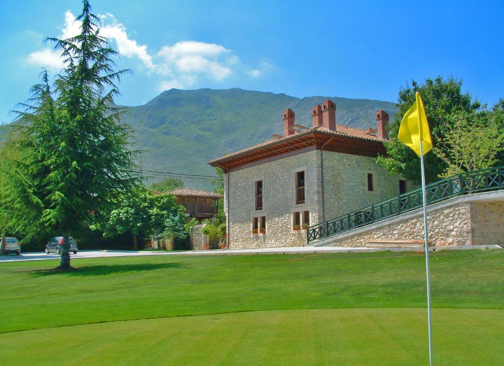 a house with a flag in front of a green yard at Hotel Aldama Golf in Quintana de Llanes