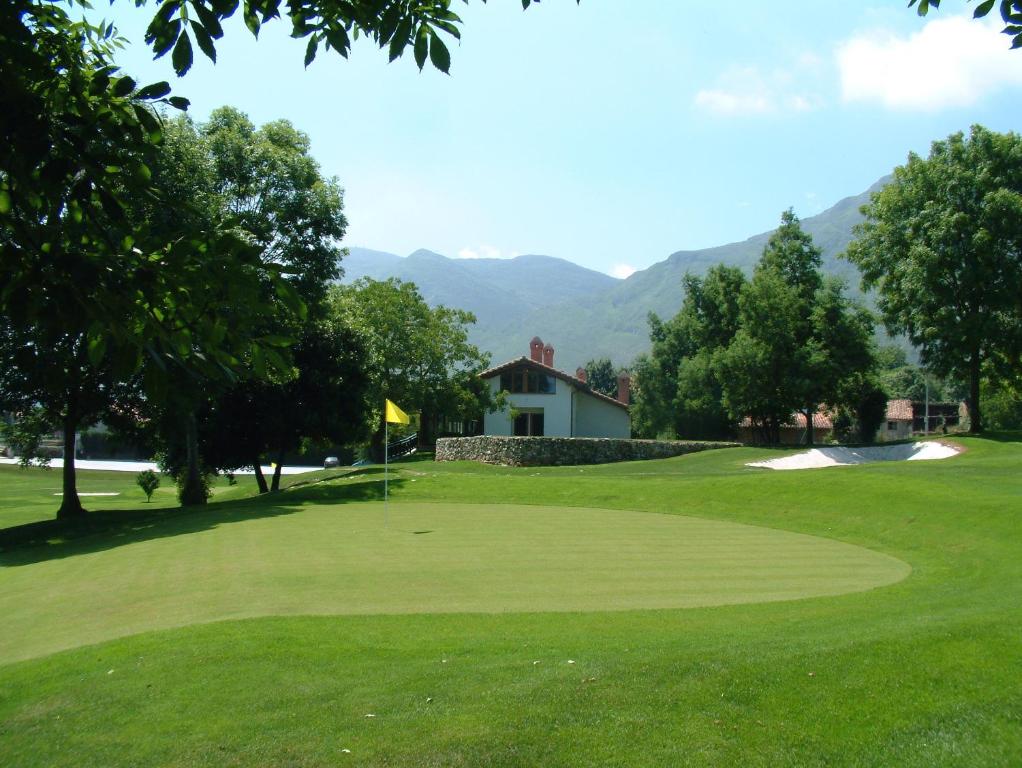 a view of a golf green with mountains in the background at Hotel Aldama Golf in Quintana de Llanes