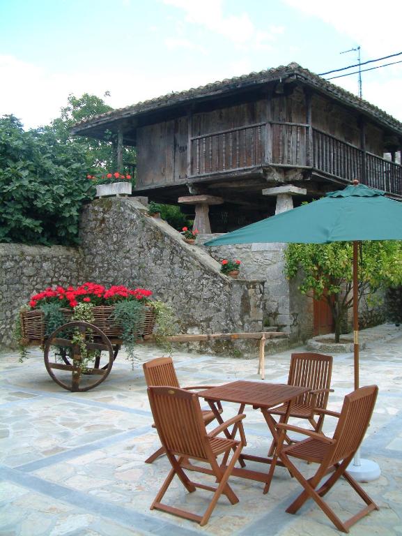 a table and chairs with an umbrella in front of a building at Hotel Aldama Golf in Quintana de Llanes